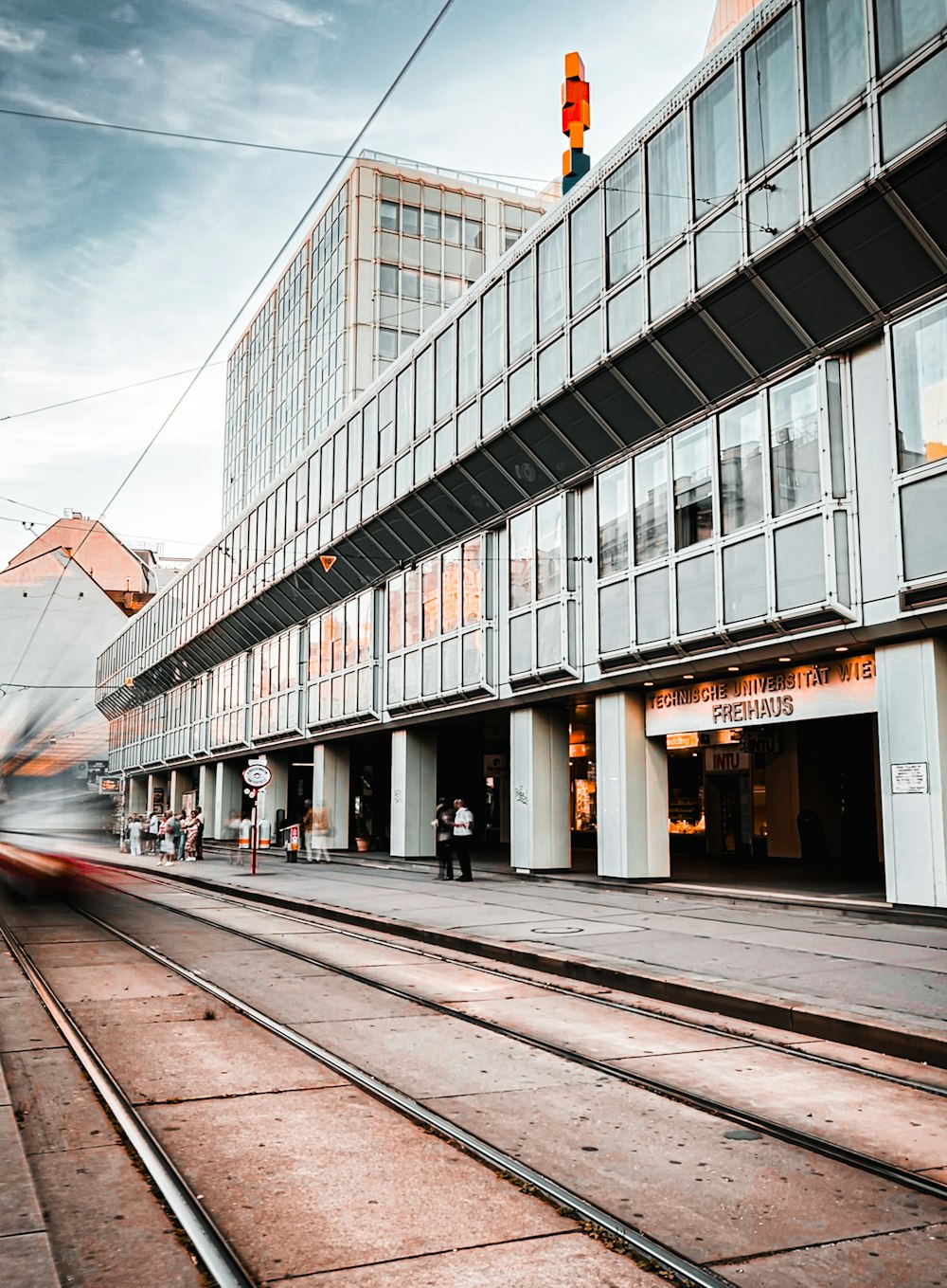 a train traveling past a tall building next to a train track