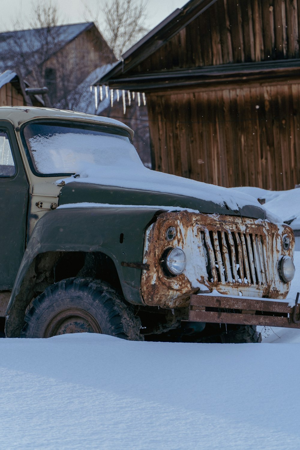 an old green truck is parked in the snow