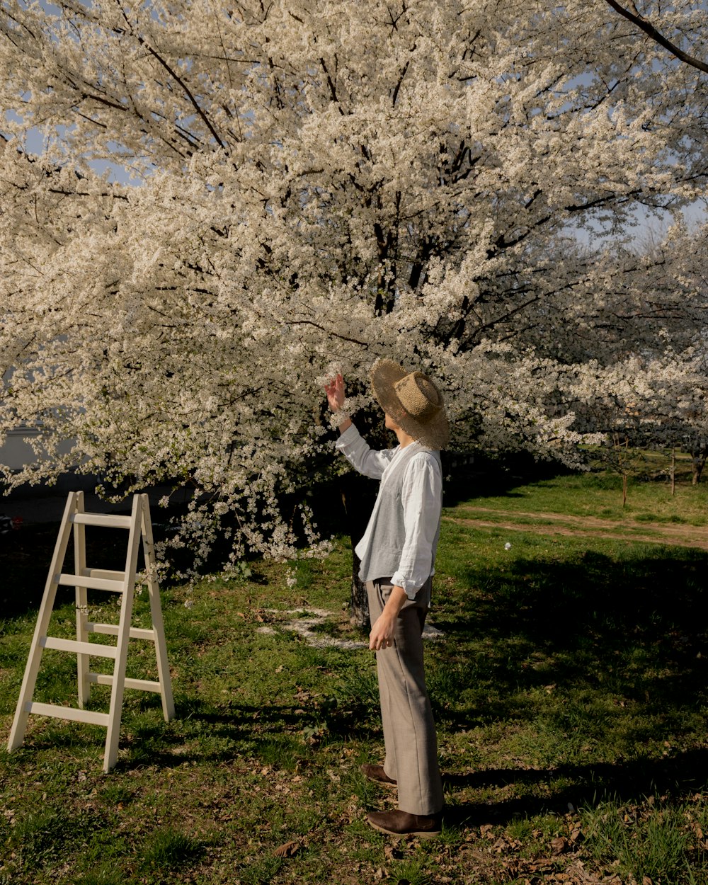 a woman standing in a field next to a tree