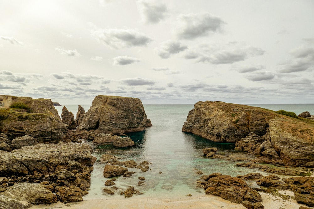 a rocky beach with a body of water between two large rocks