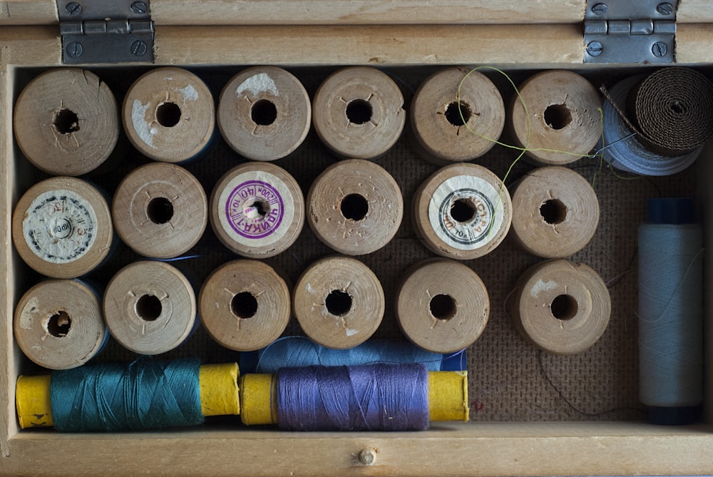 plusieurs bobines de fil et bobines de fil dans une boîte en bois