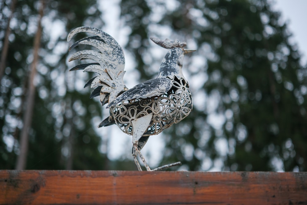 a statue of a bird on top of a wooden fence