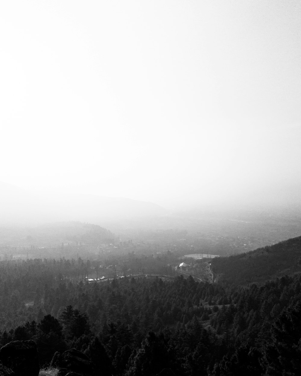 a black and white photo of a foggy mountain