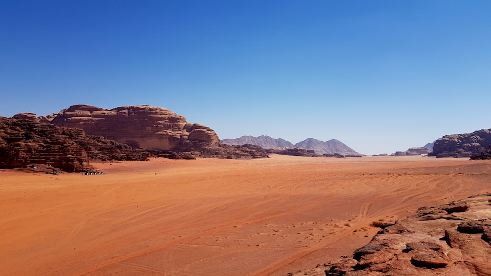 a sandy desert with mountains in the background