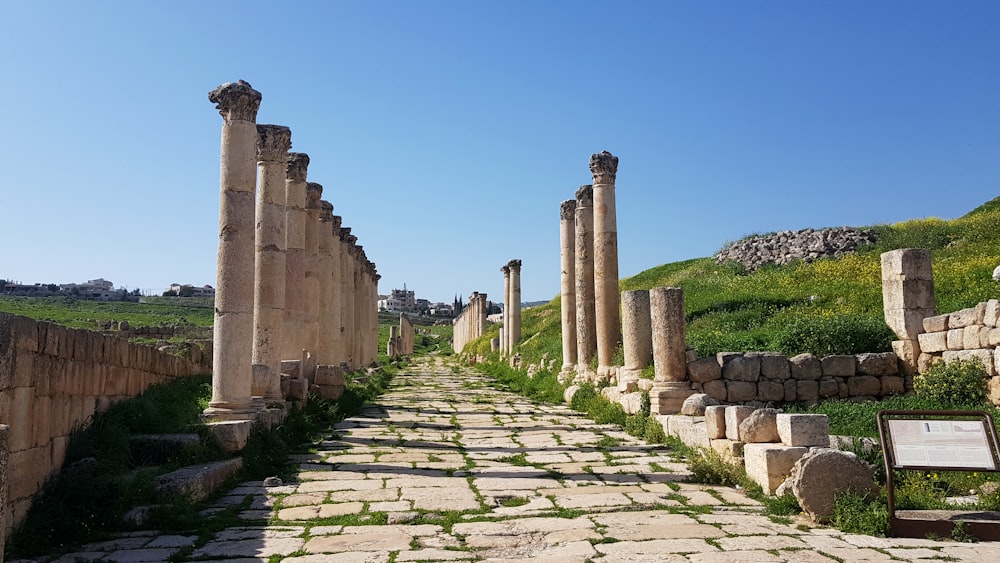 a stone path lined with columns and a sign