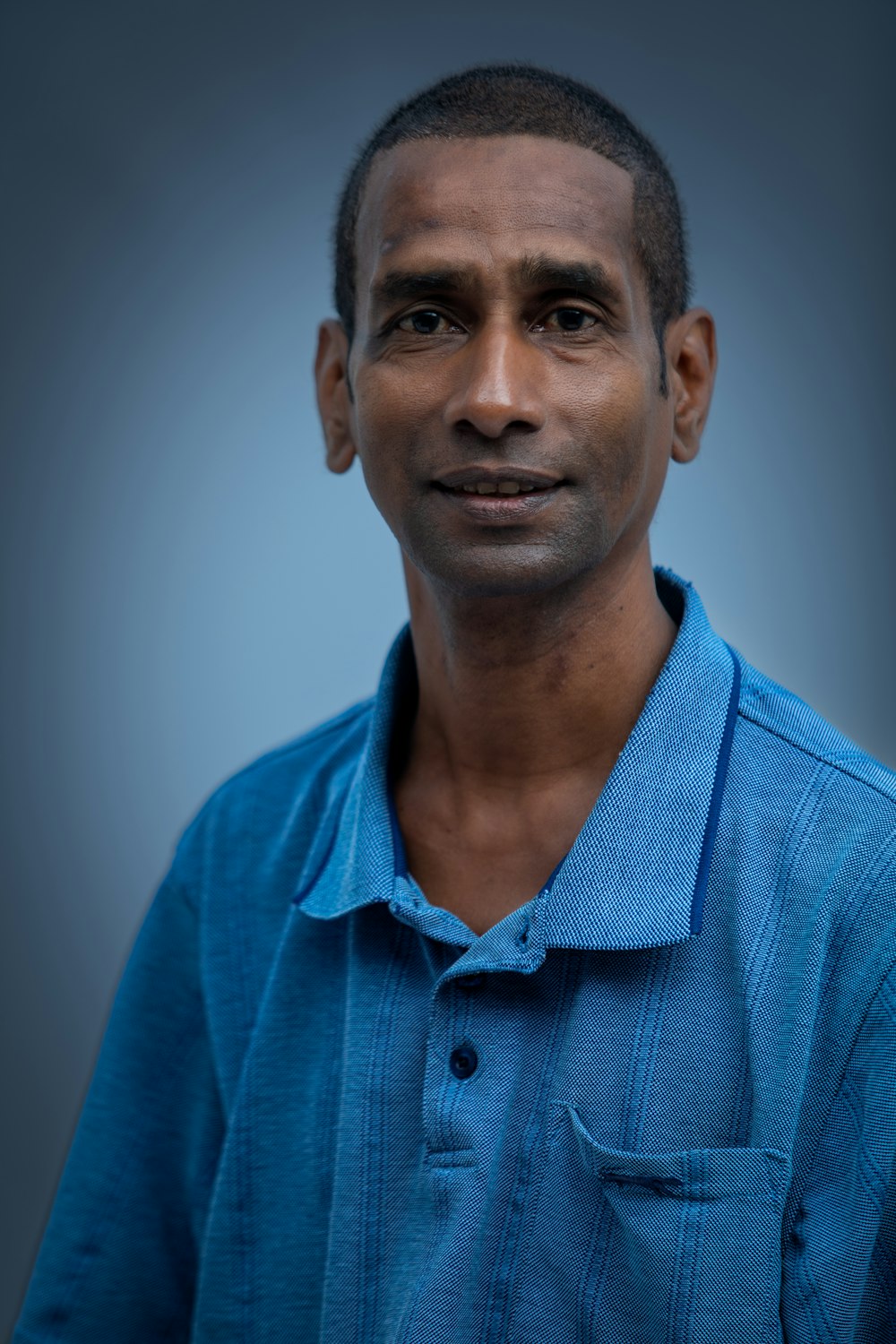 a man in a blue shirt posing for a picture