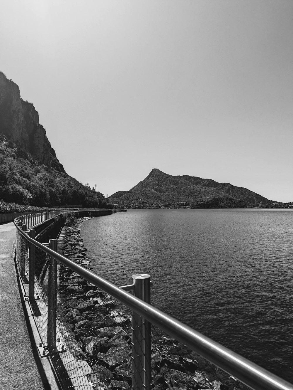 a black and white photo of a road next to a body of water