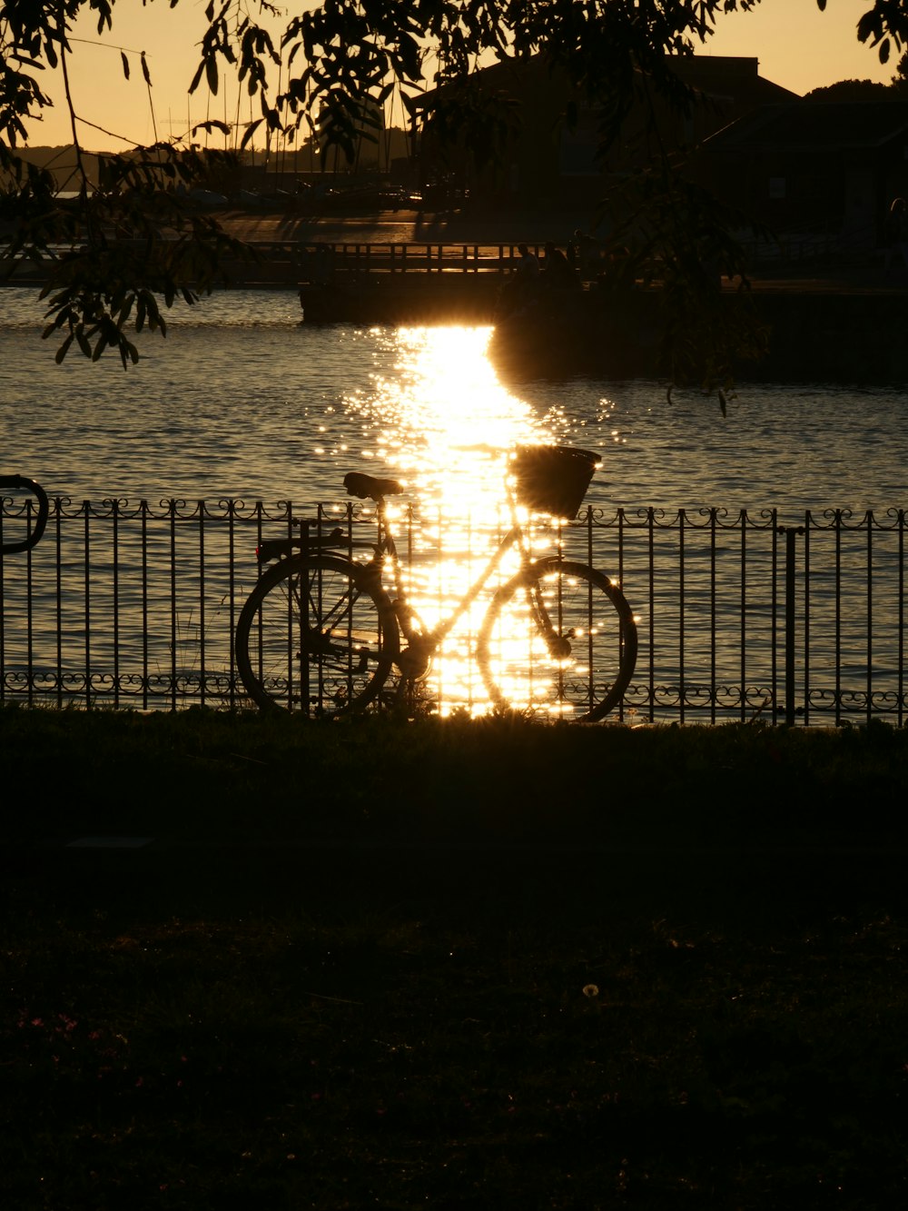 a bike parked next to a fence near a body of water