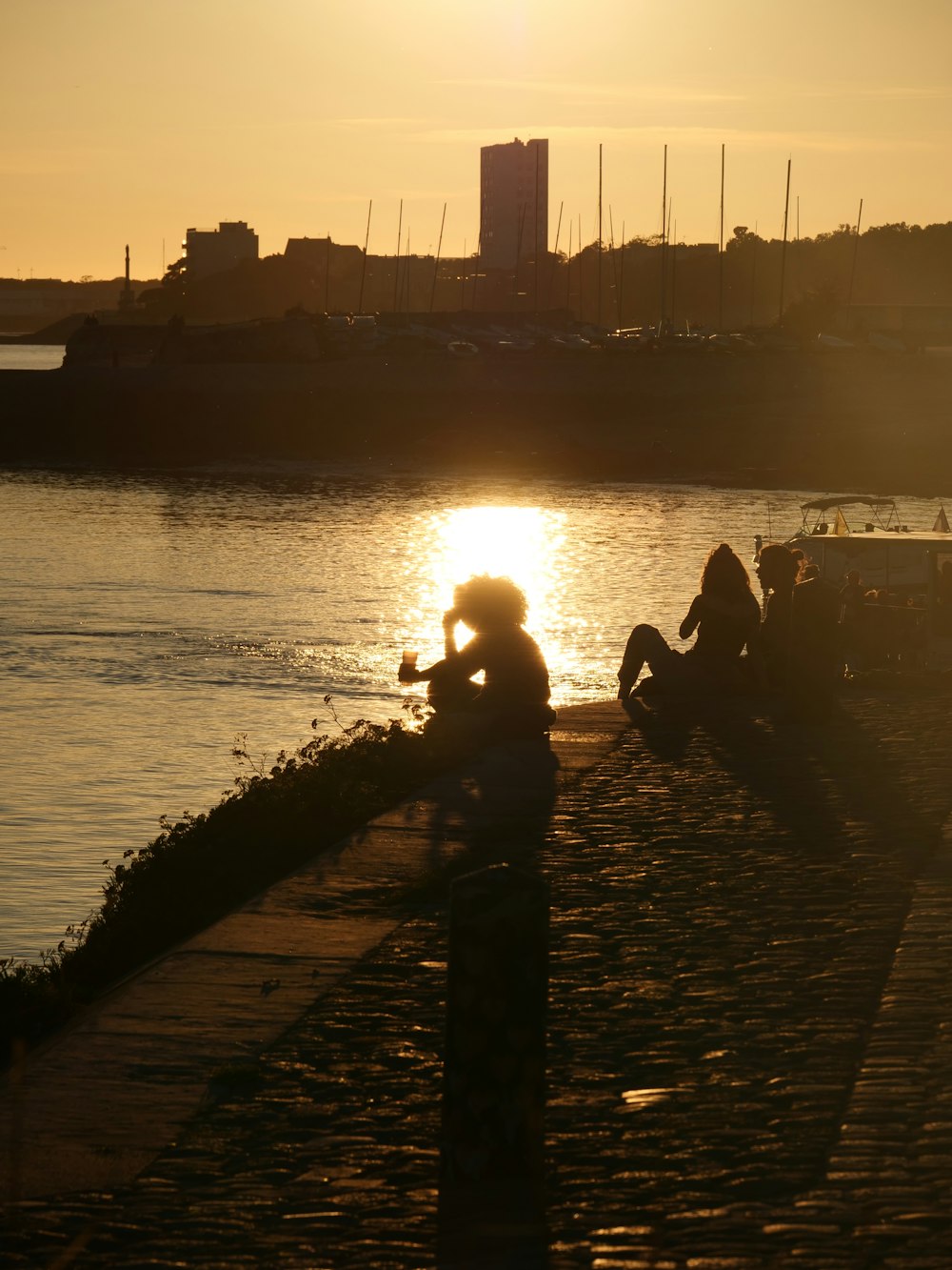 a couple of people sitting on a dock next to a body of water