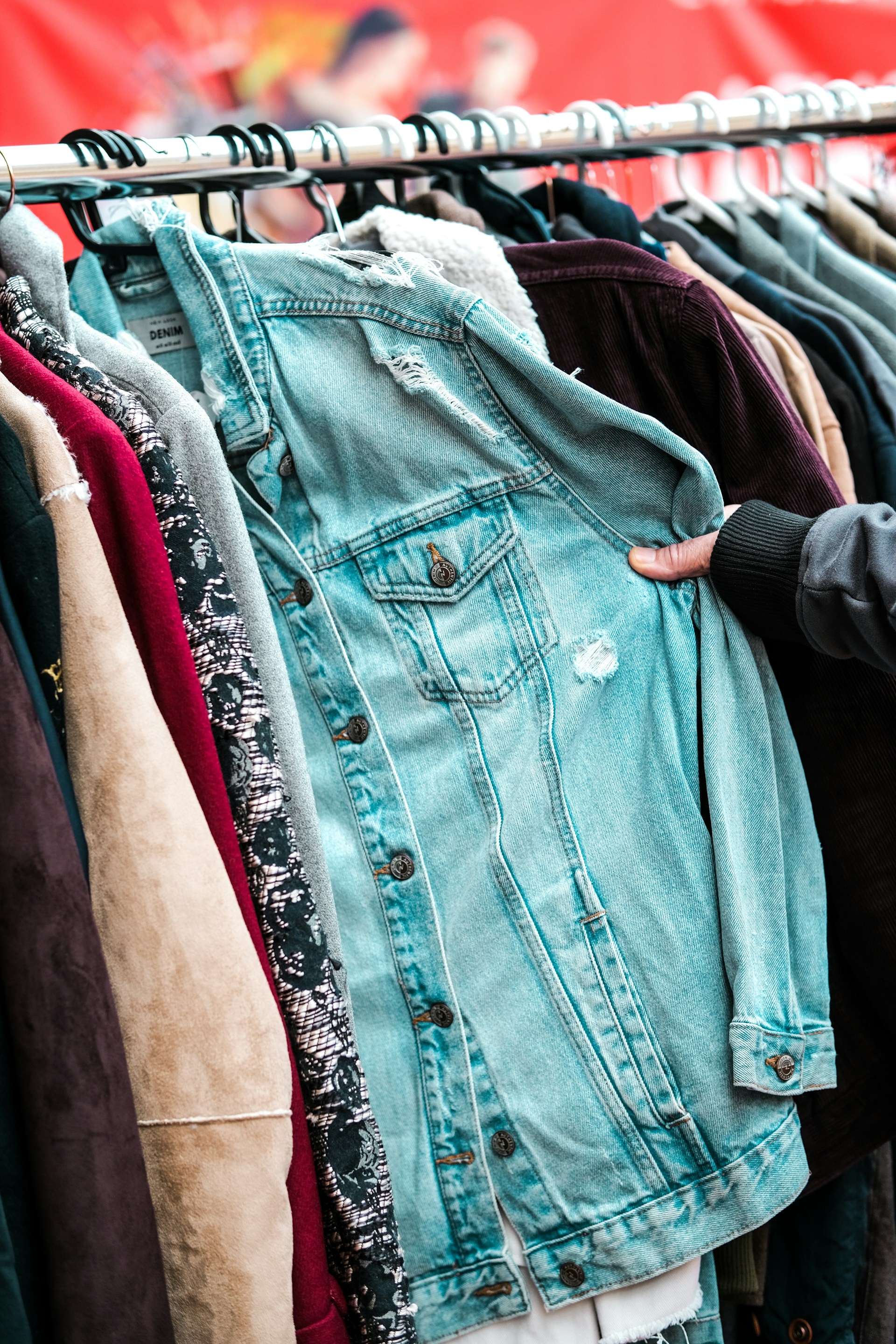 a person holding a jacket on a rack
