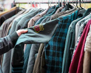 a person holding a shirt in front of a rack of shirts