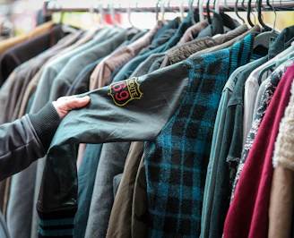 a person holding a shirt in front of a rack of shirts