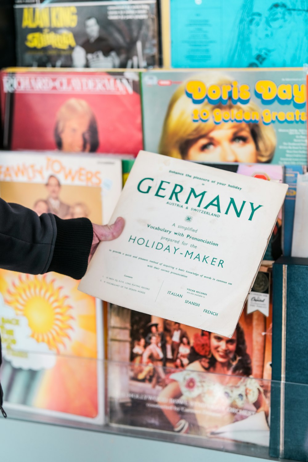 a person holding a sheet of paper in front of a wall of records