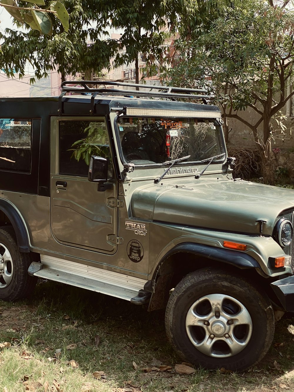 a jeep is parked in the shade of a tree
