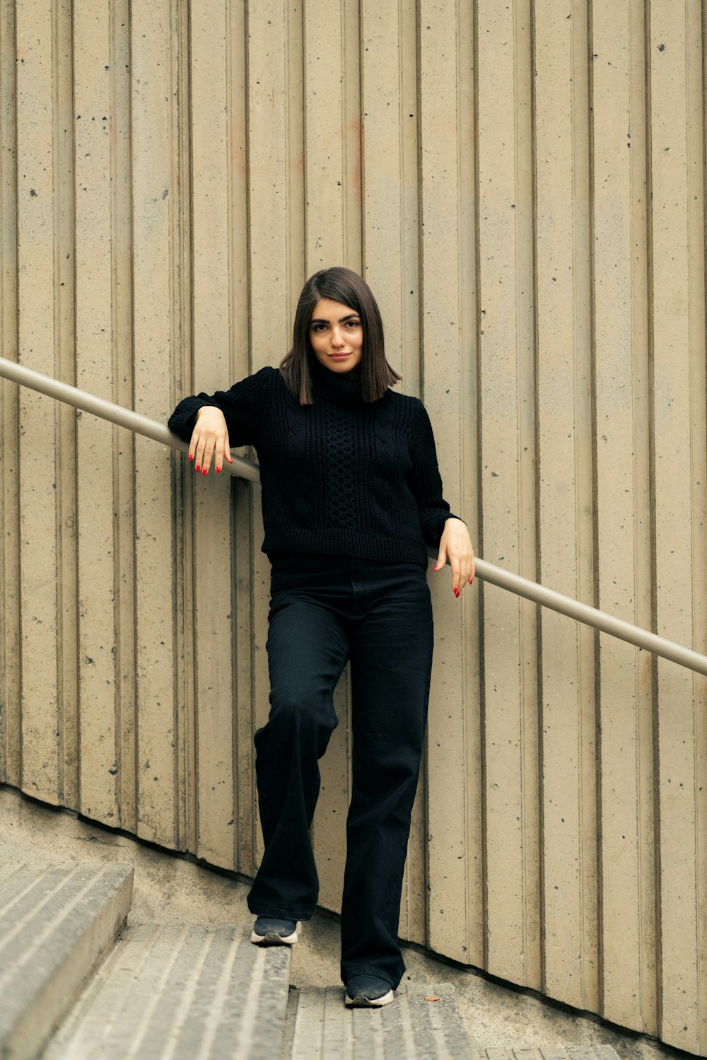 a woman leaning against a wall leaning against a rail