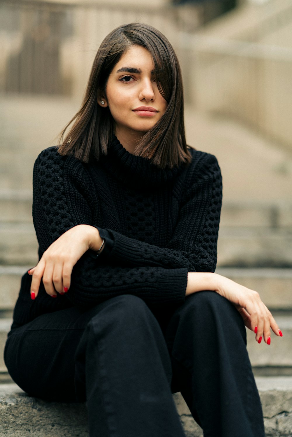 a woman sitting on steps wearing a black sweater and black pants