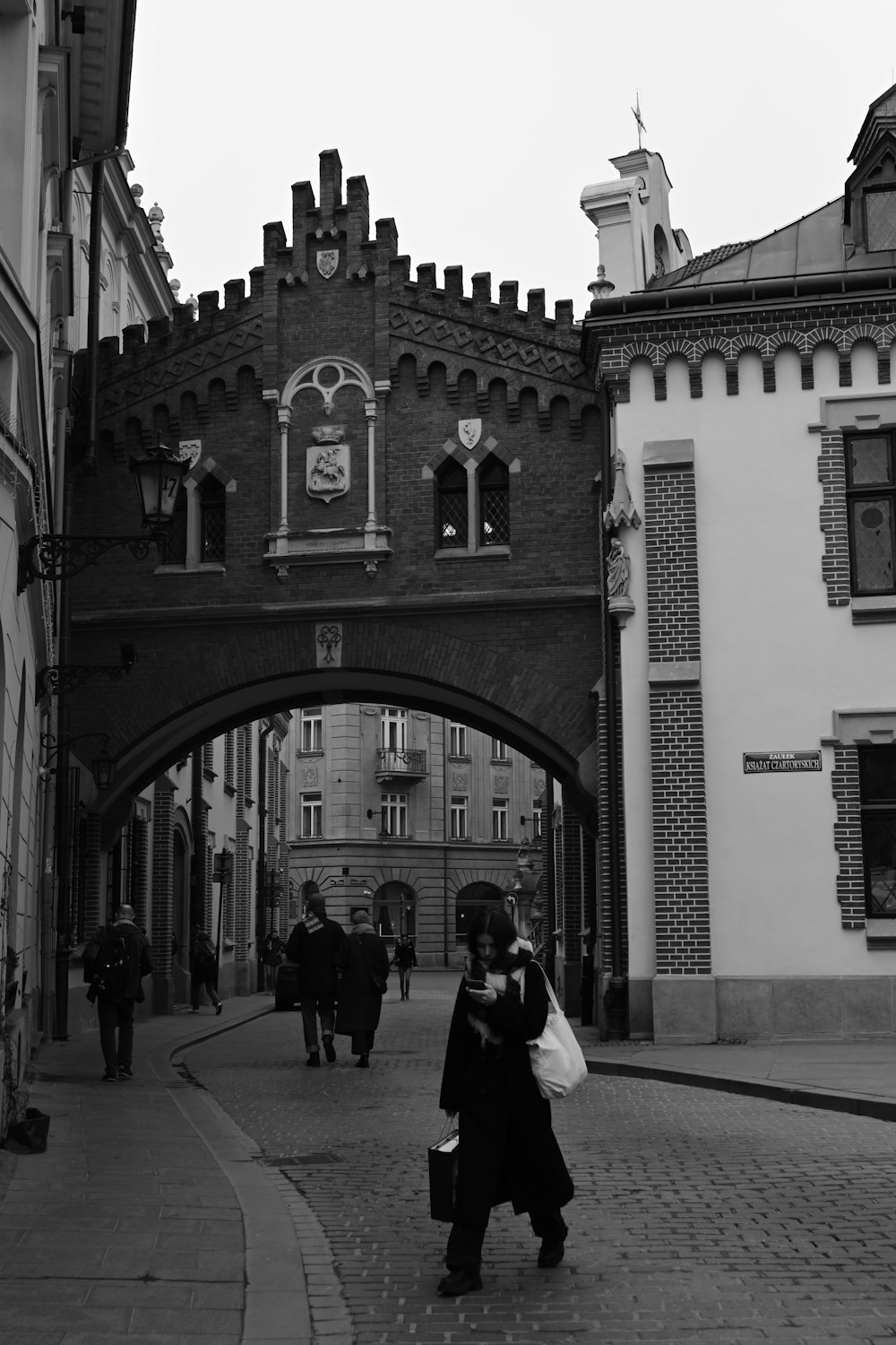 a black and white photo of people walking under a bridge