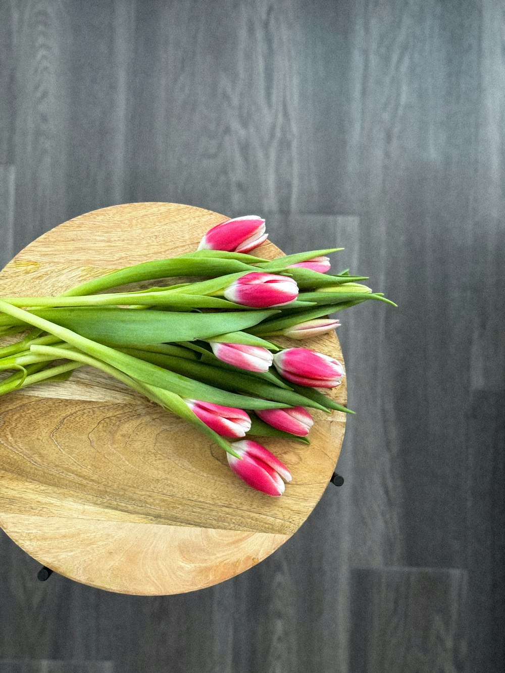 a bunch of pink and white tulips on a wooden table