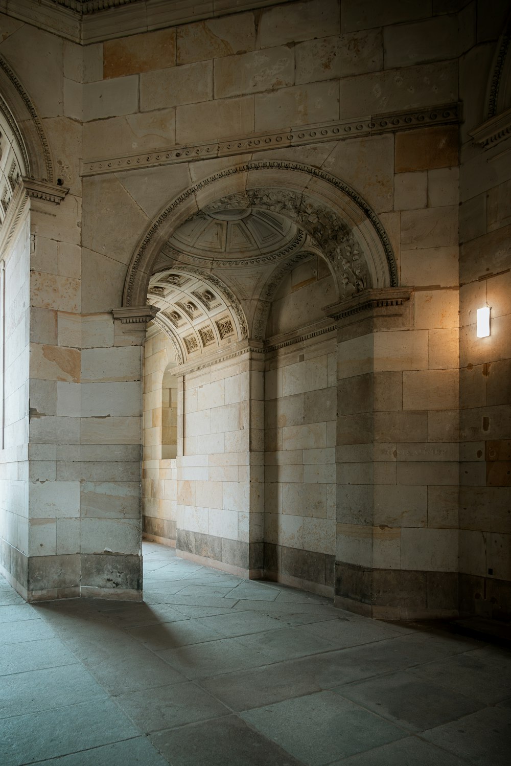 a hallway with a stone wall and arched doorway