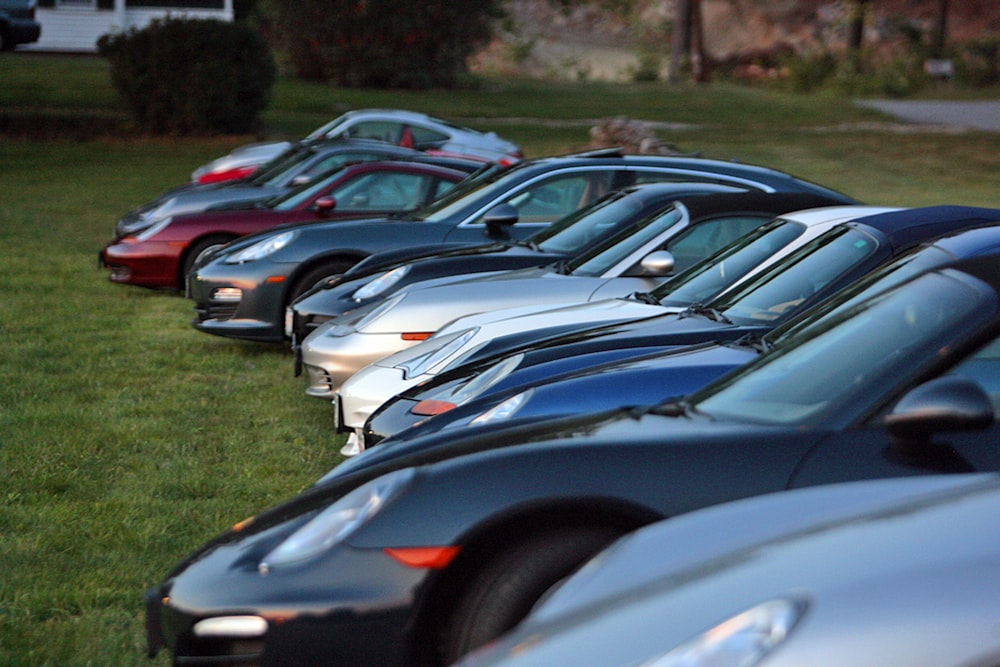 a row of parked cars sitting on top of a lush green field