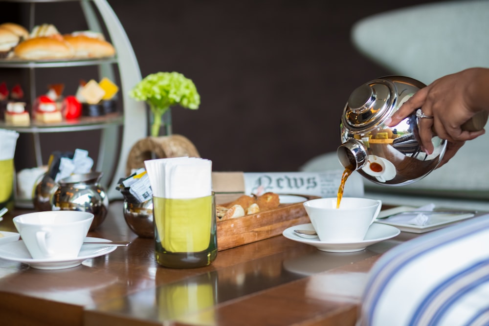 a person pouring tea into a cup on a table