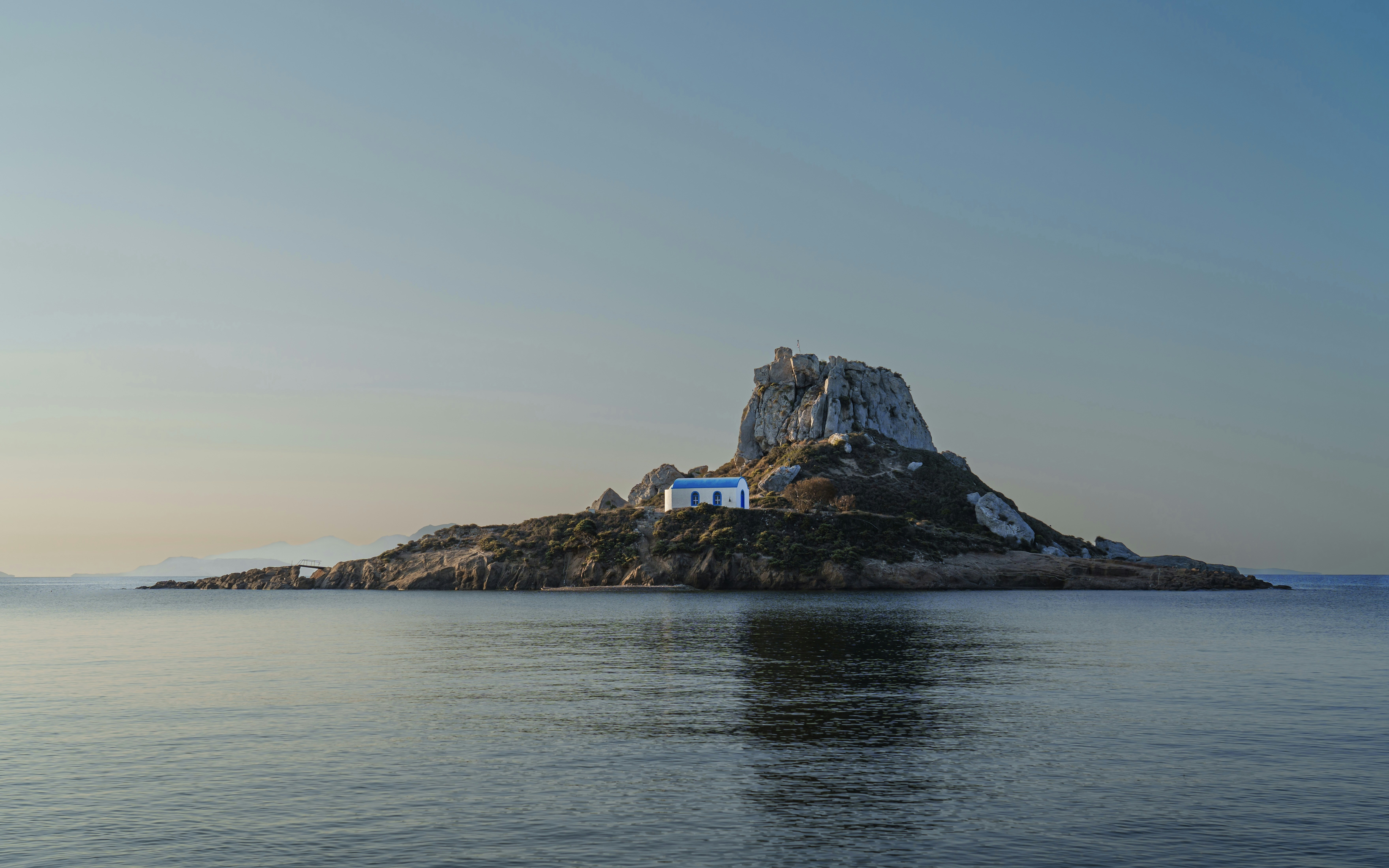 an island with a house on top of it in the middle of the ocean