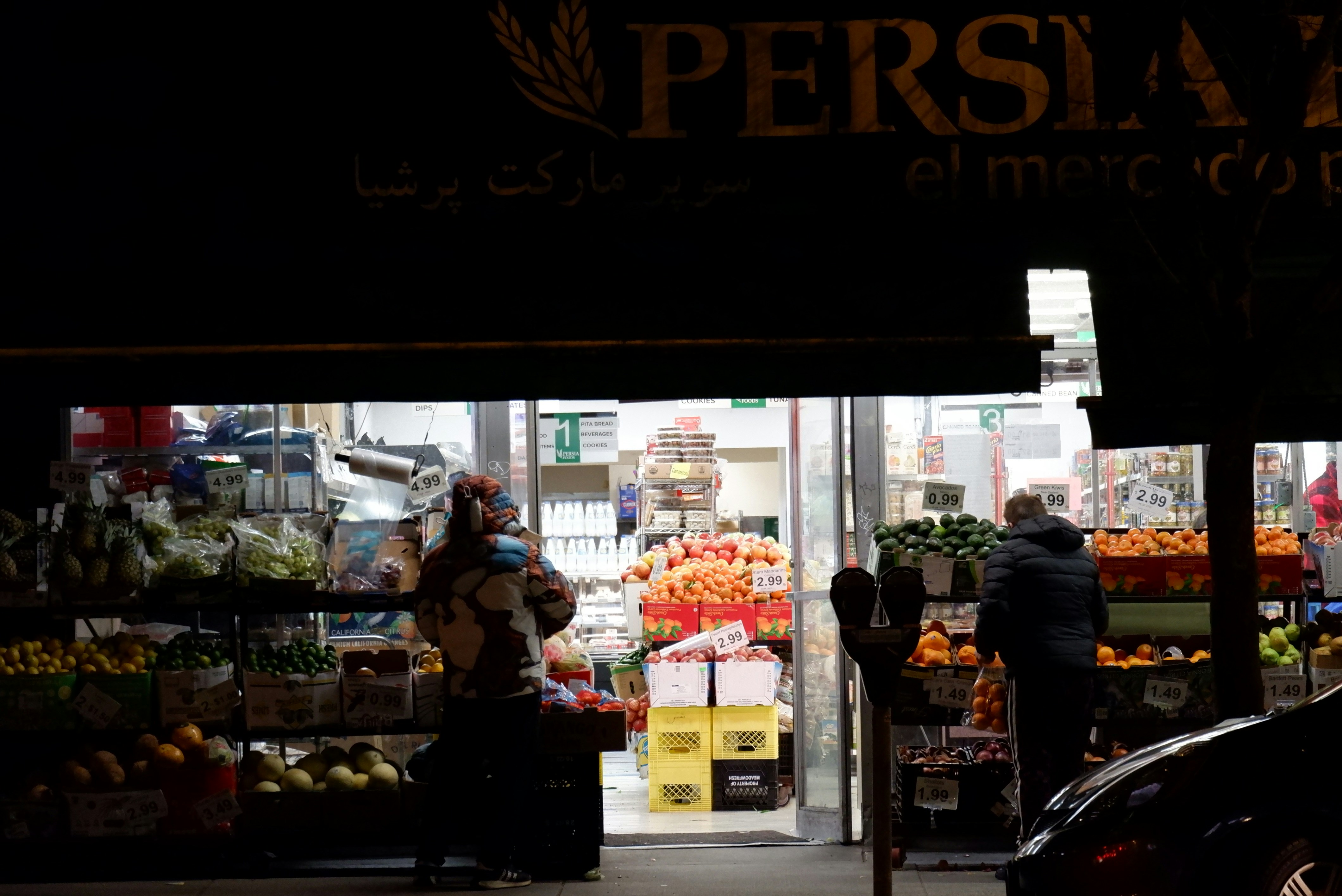 a person standing in front of a fruit and vegetable stand