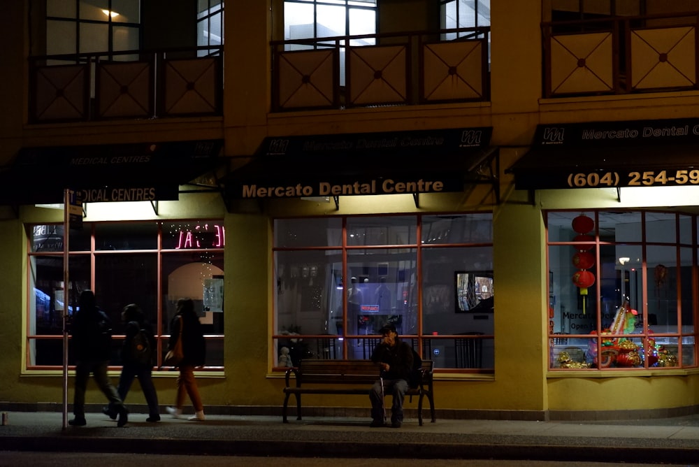 a group of people walking past a building at night