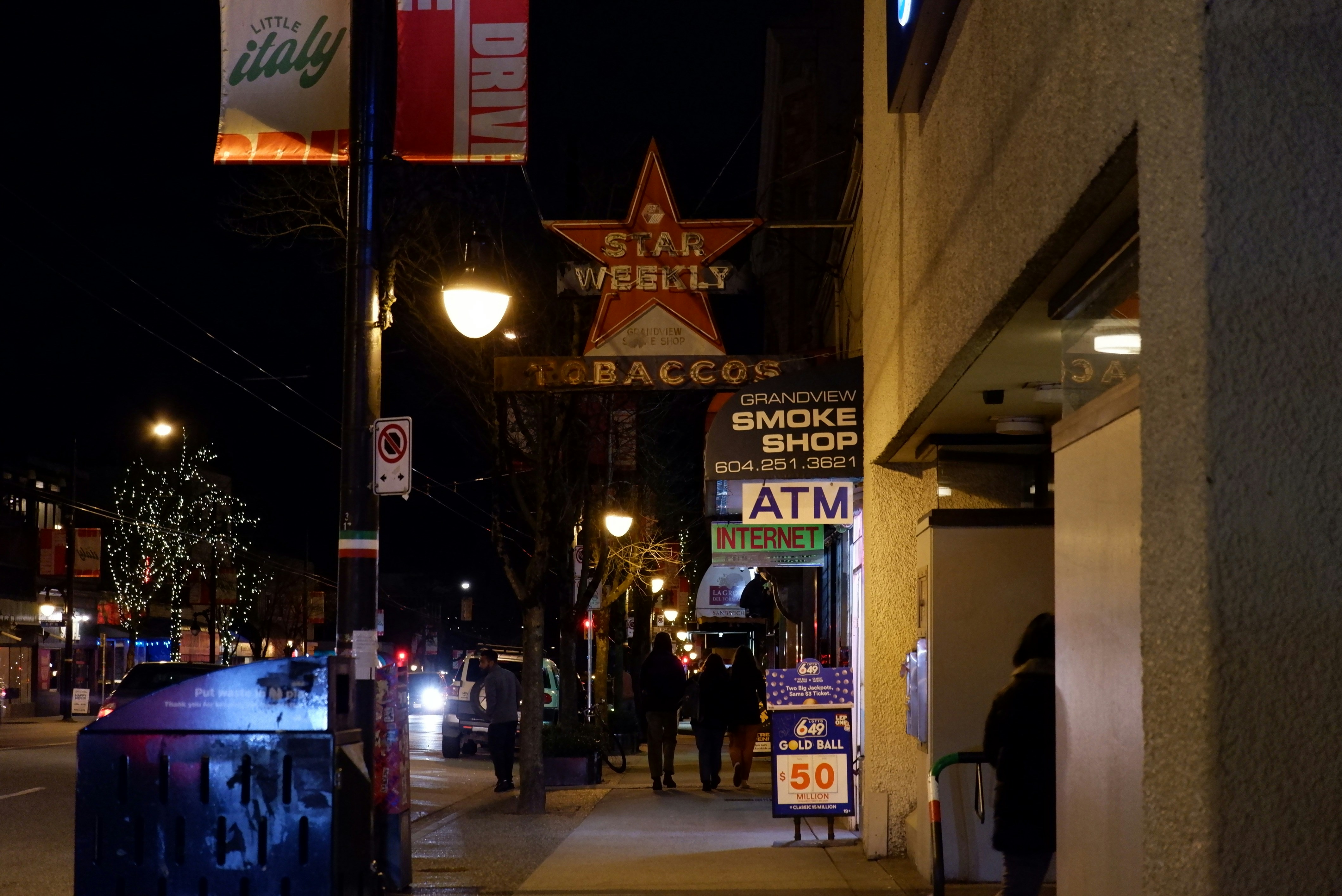 a city street at night with people walking on the sidewalk
