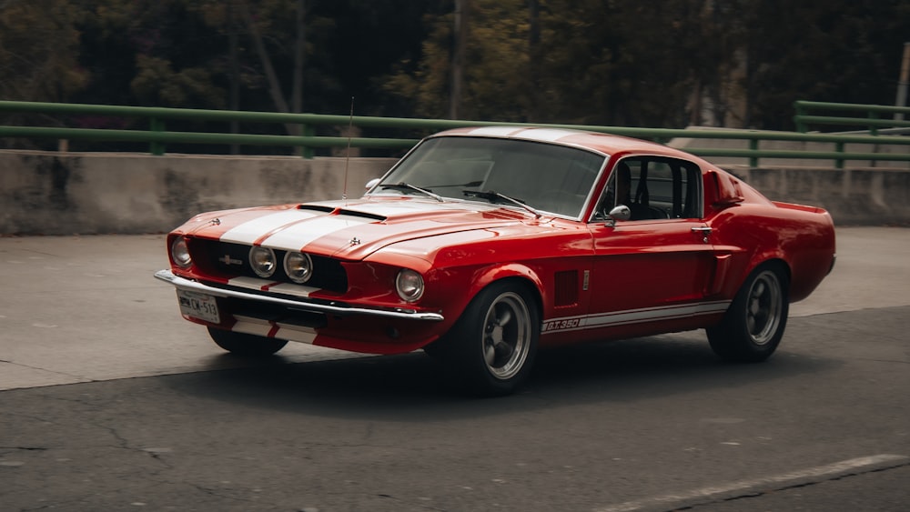a red mustang car driving down a street