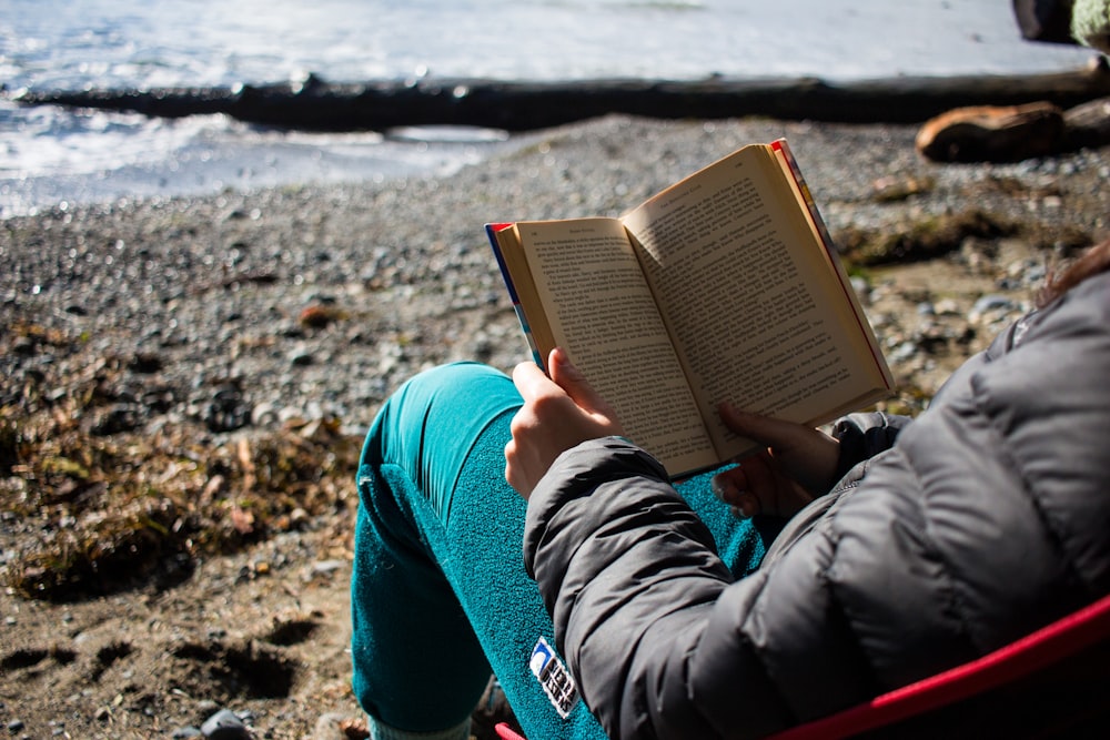 a person sitting on a beach reading a book