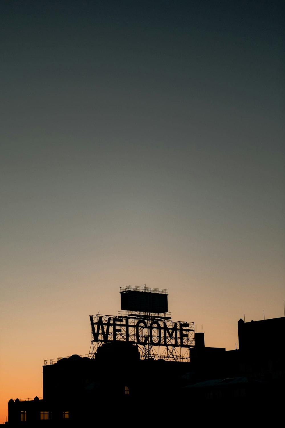a welcome sign is silhouetted against the evening sky