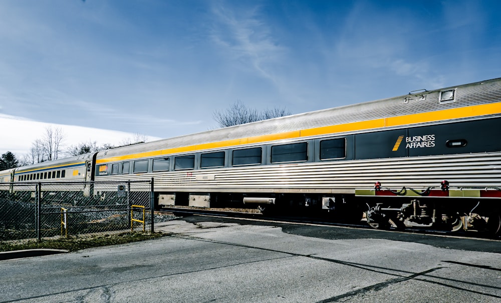 un tren plateado y amarillo que viaja por las vías del tren