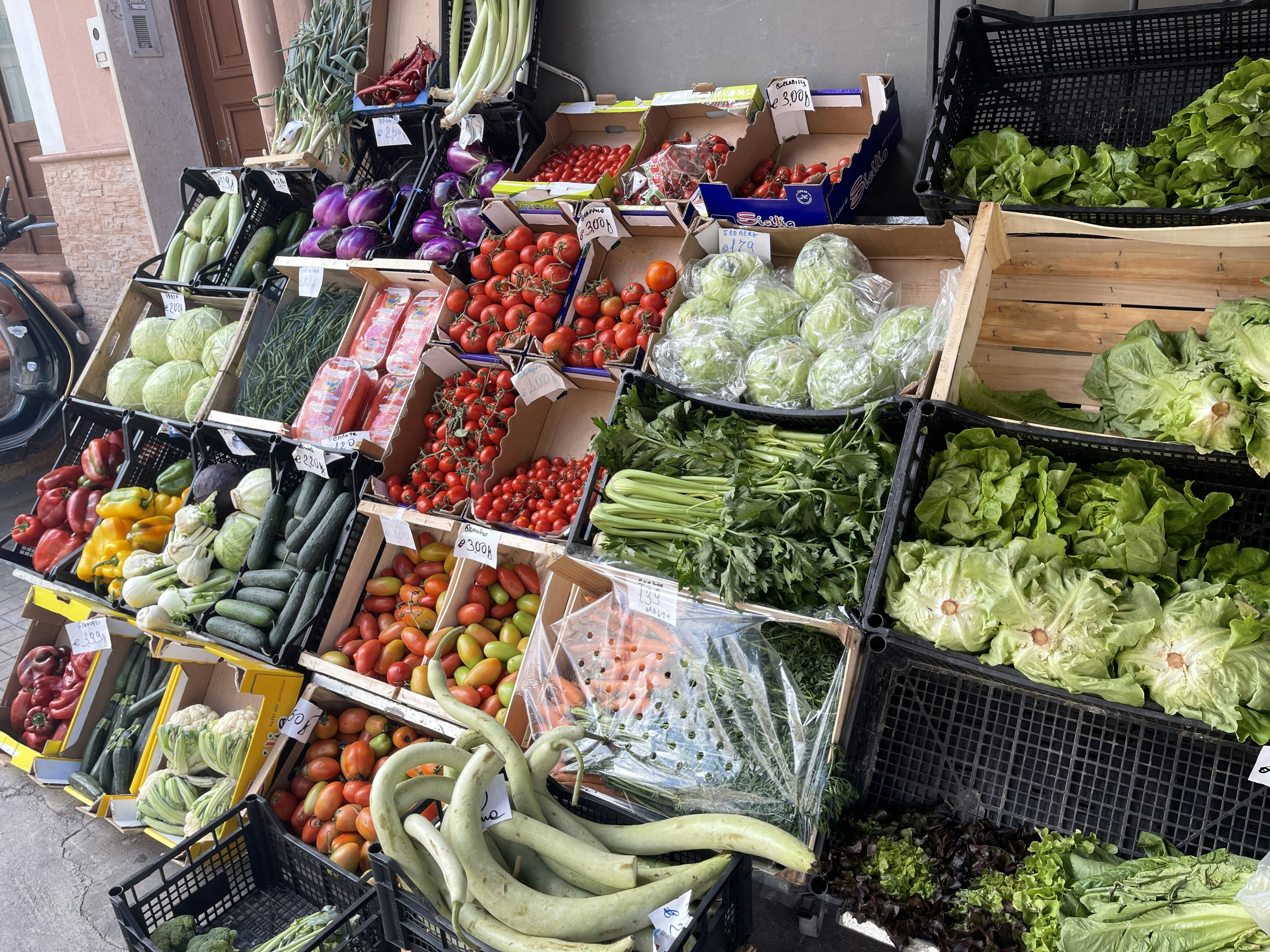 Colourful assortment of fresh African vegetables and fruits on a market stall, vibrant greens and yellows in bright daylight