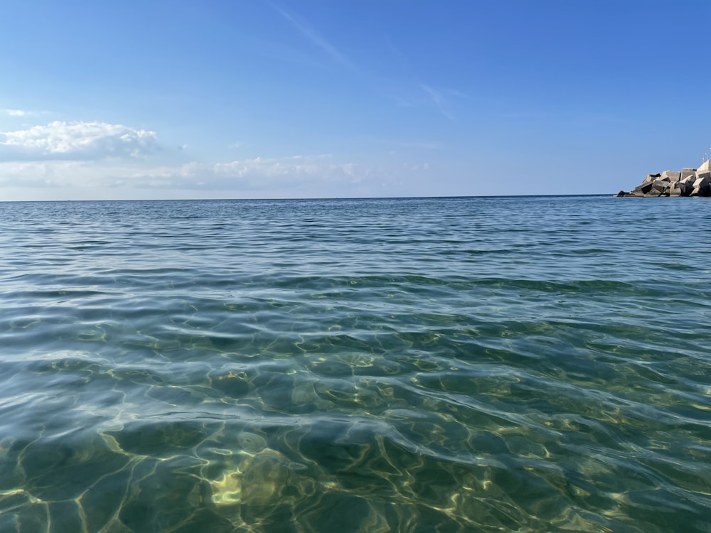 a body of water with rocks in the background