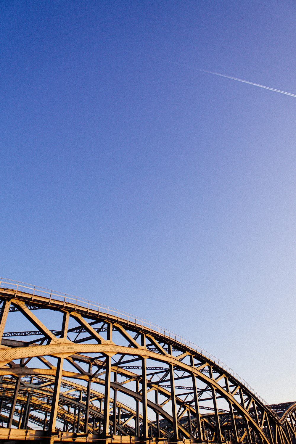 a plane flying over a bridge on a sunny day
