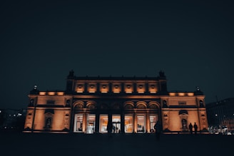 a building lit up at night with people standing outside