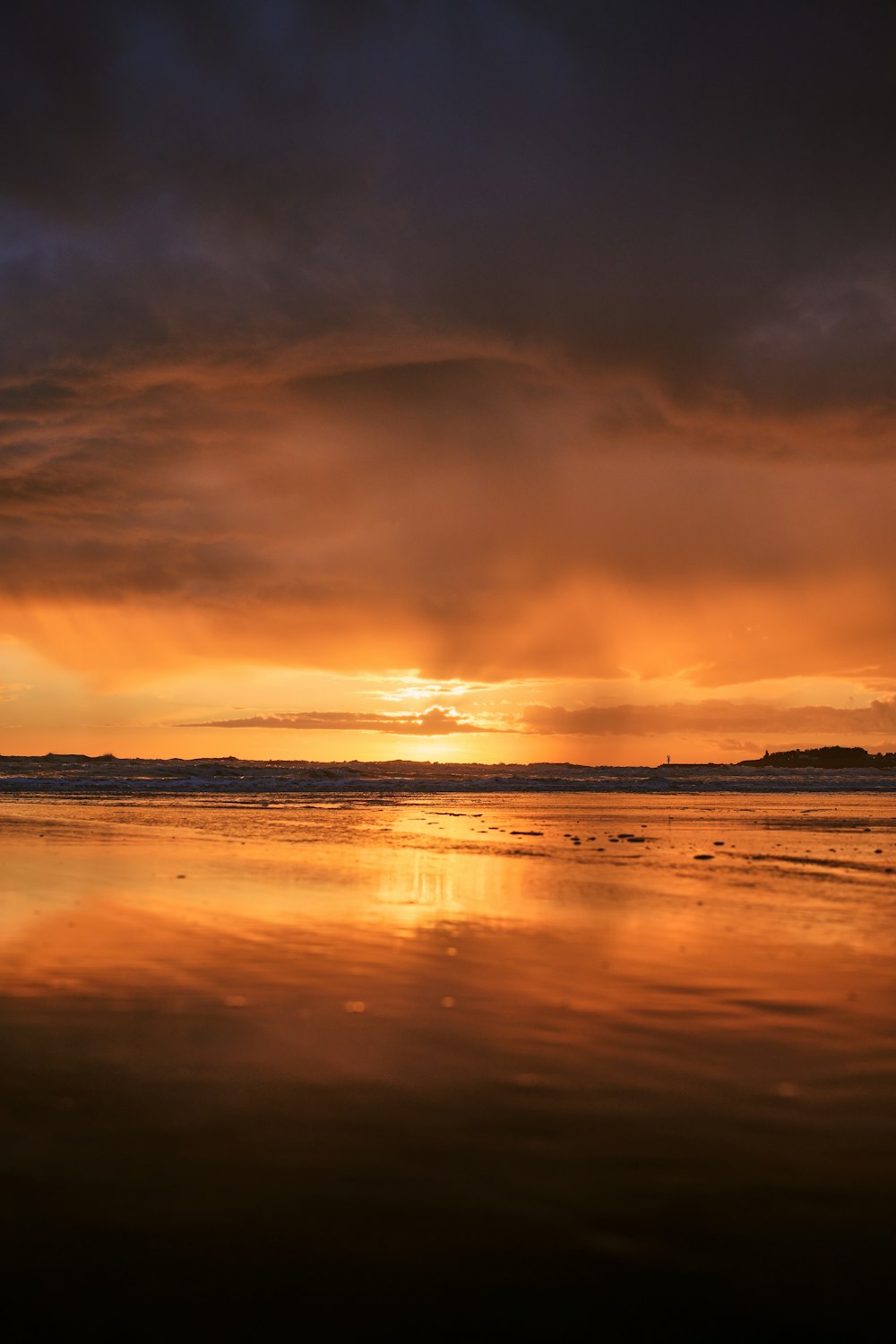 the sun is setting over the water on the beach