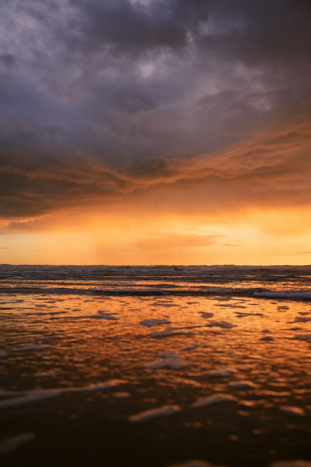 the sun is setting over the ocean on a cloudy day