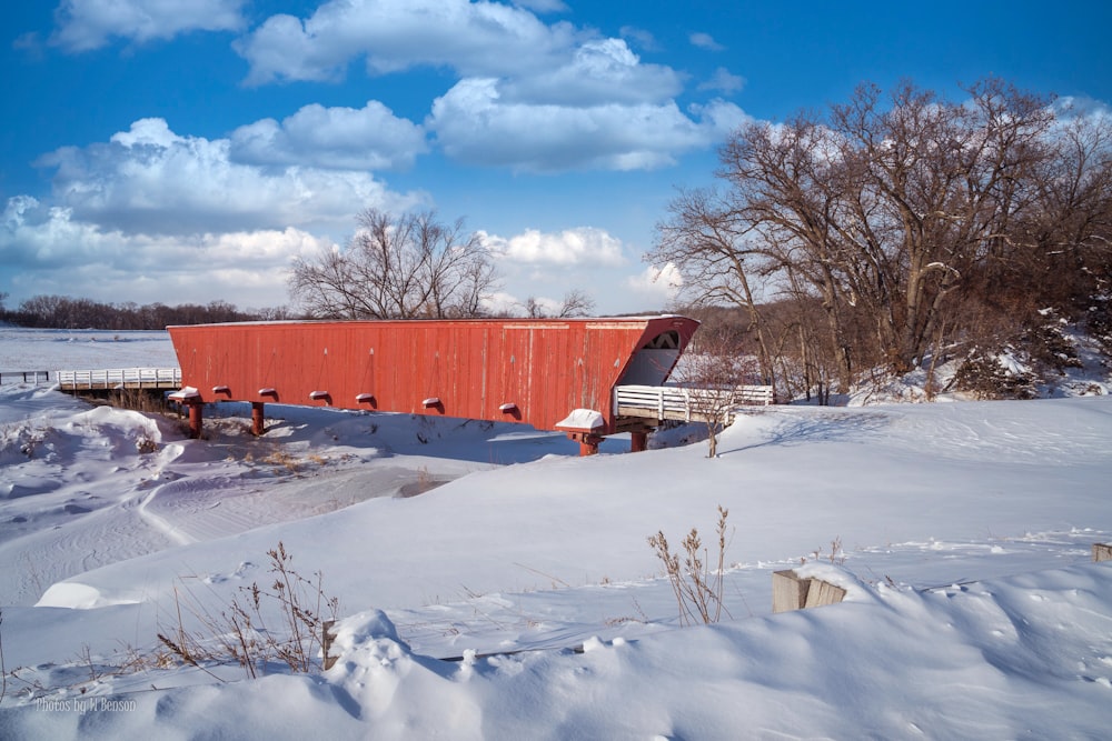 a red covered bridge in the middle of a snowy field