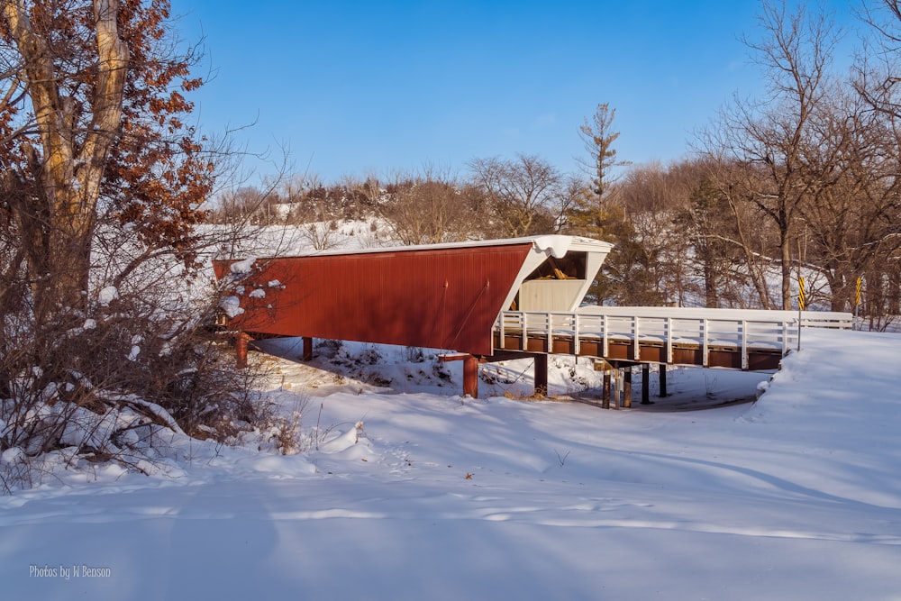 a red boat sitting on top of a snow covered field