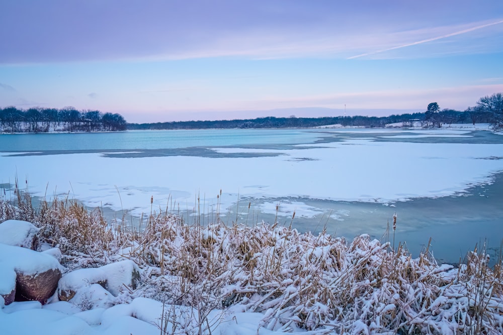 a frozen lake surrounded by snow covered ground