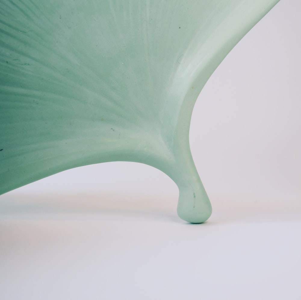 a large green vase sitting on top of a white table