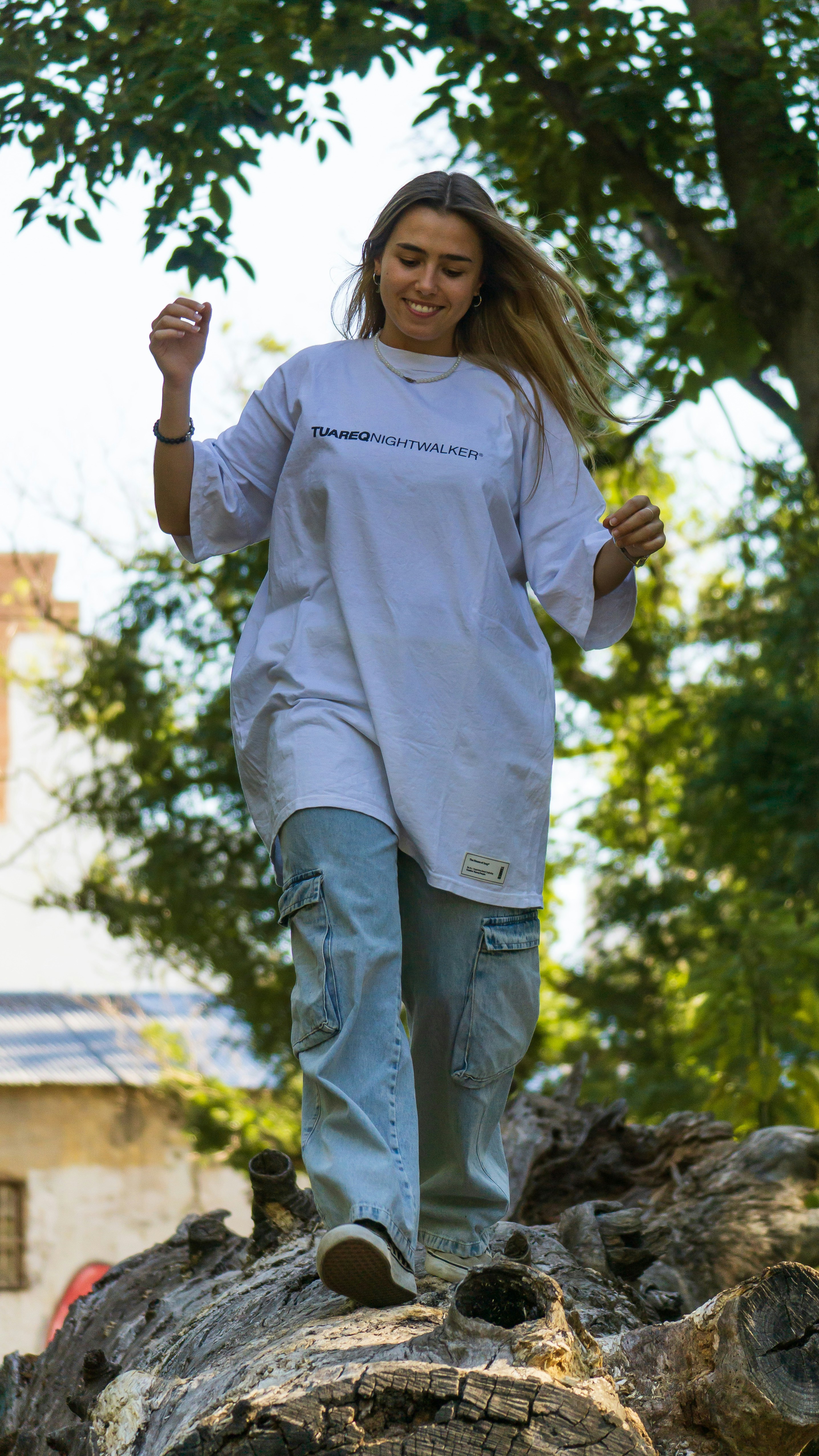 a woman in a white shirt is walking on a rock