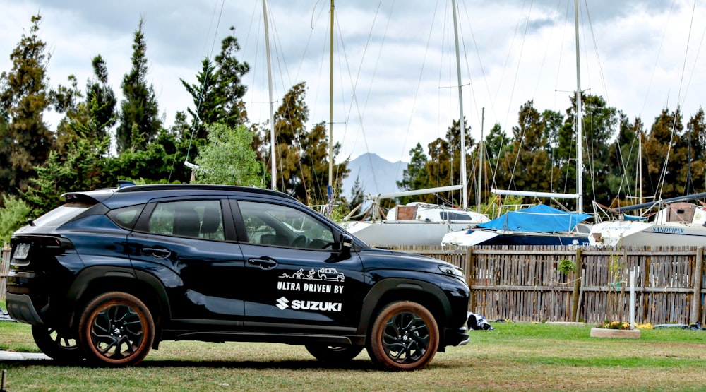 a black suv parked in the grass near a fence