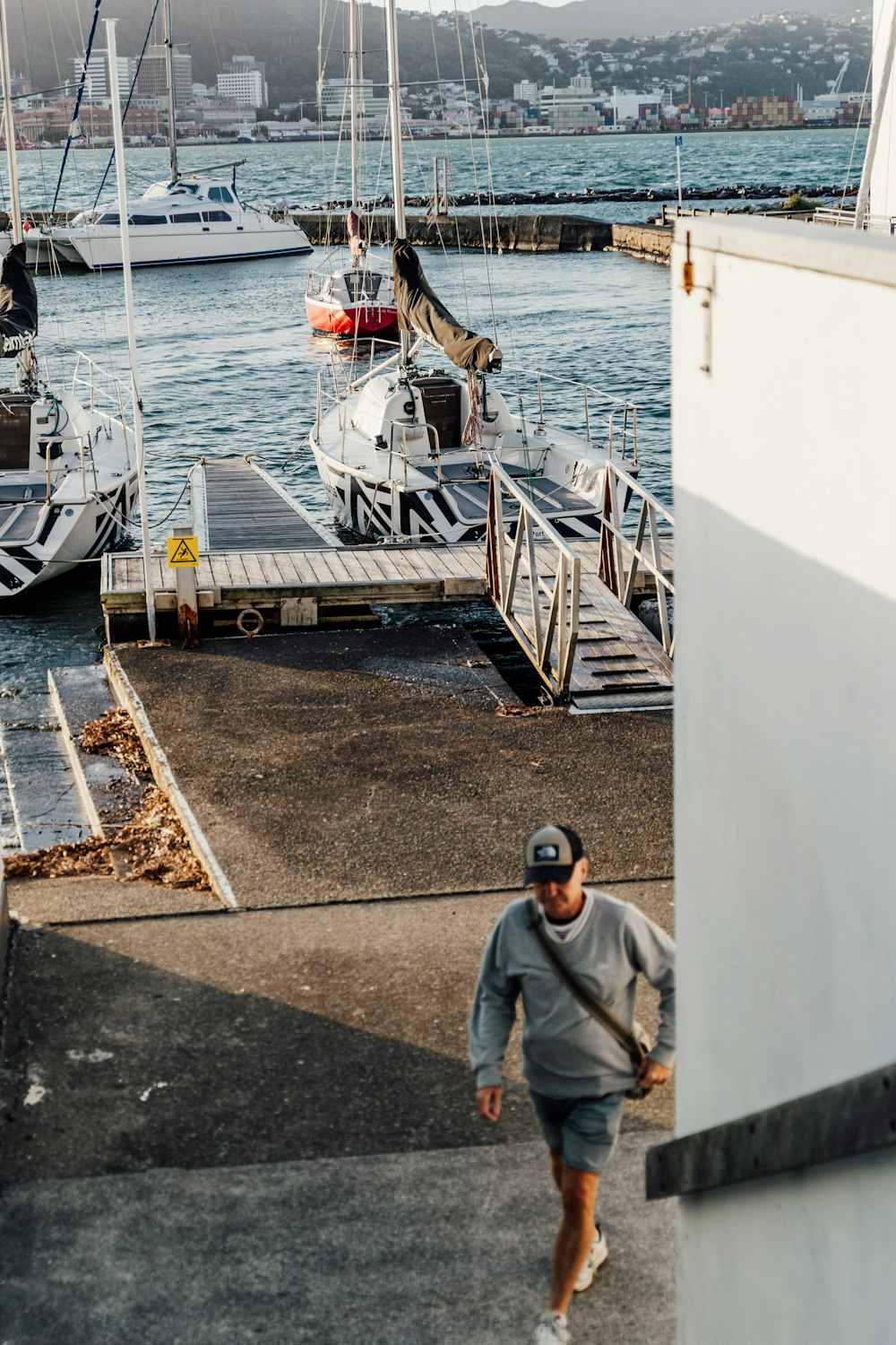 a man walking towards a dock with boats in the water