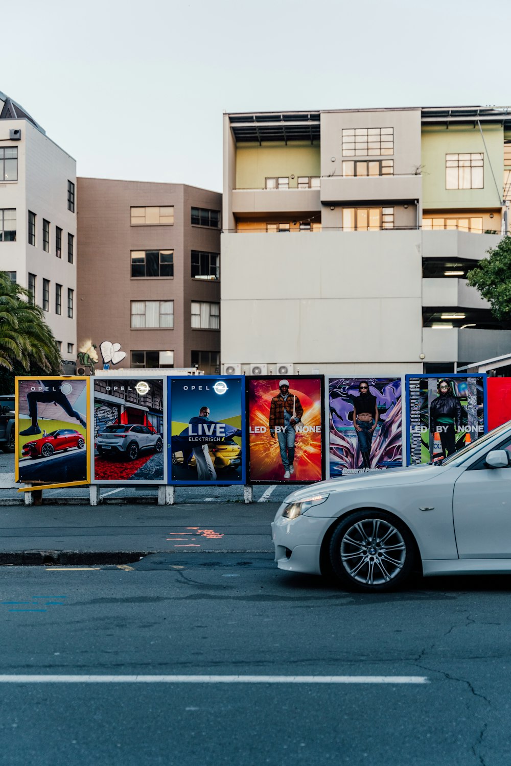 a white car parked in front of a tall building