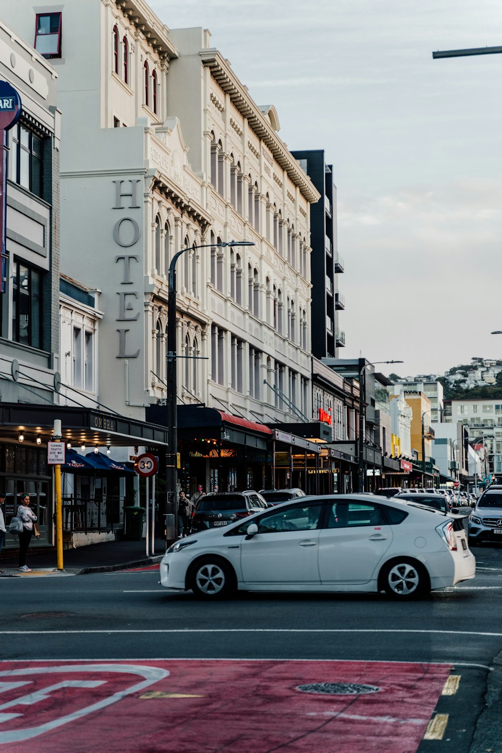 a white car driving down a street next to tall buildings