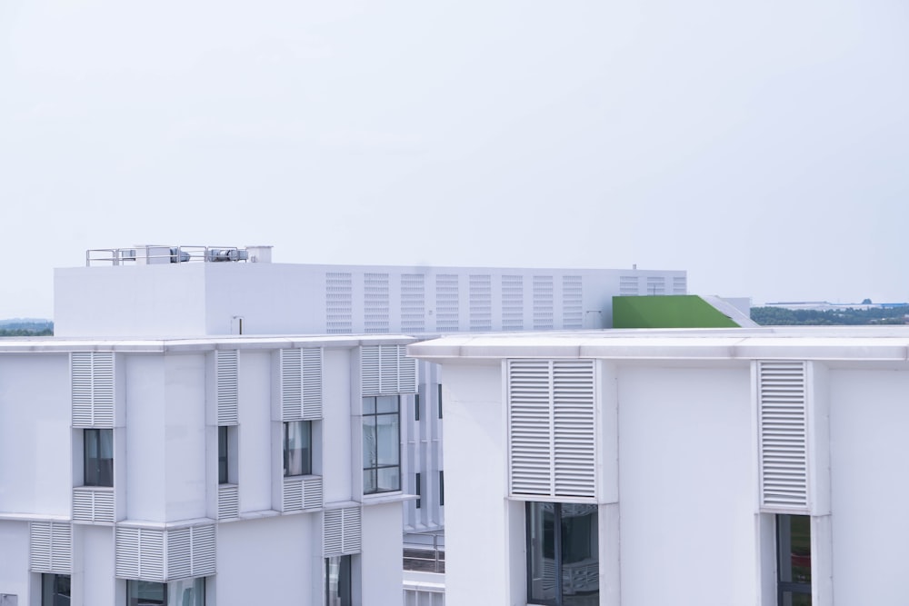 a white building with white shutters and a green roof