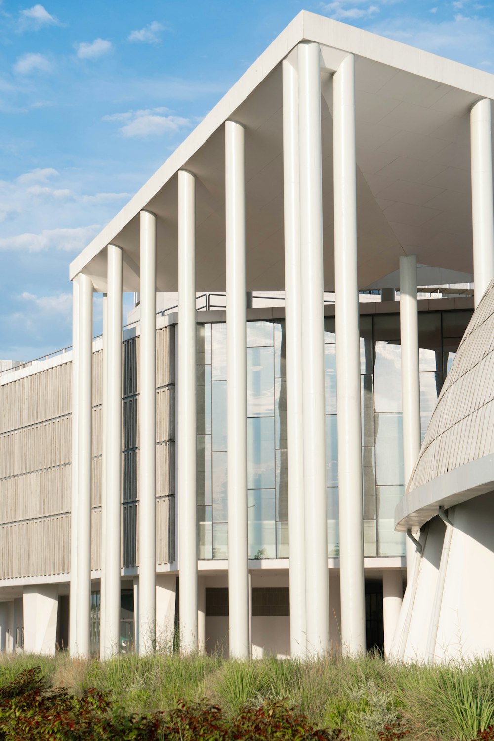 a white building with columns and grass in front of it